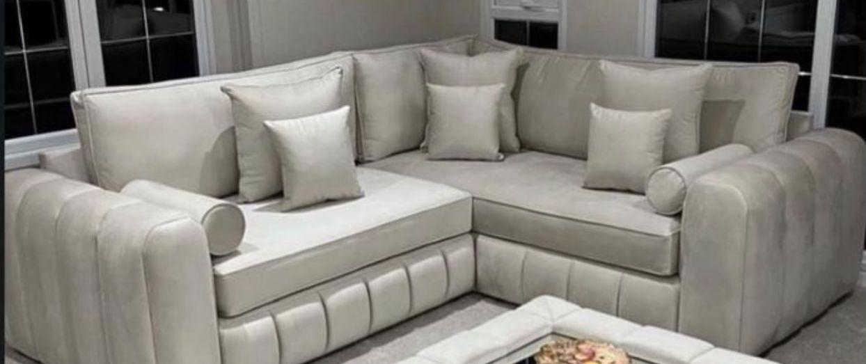 Light corner sofa with padded arms and loose back cushions.