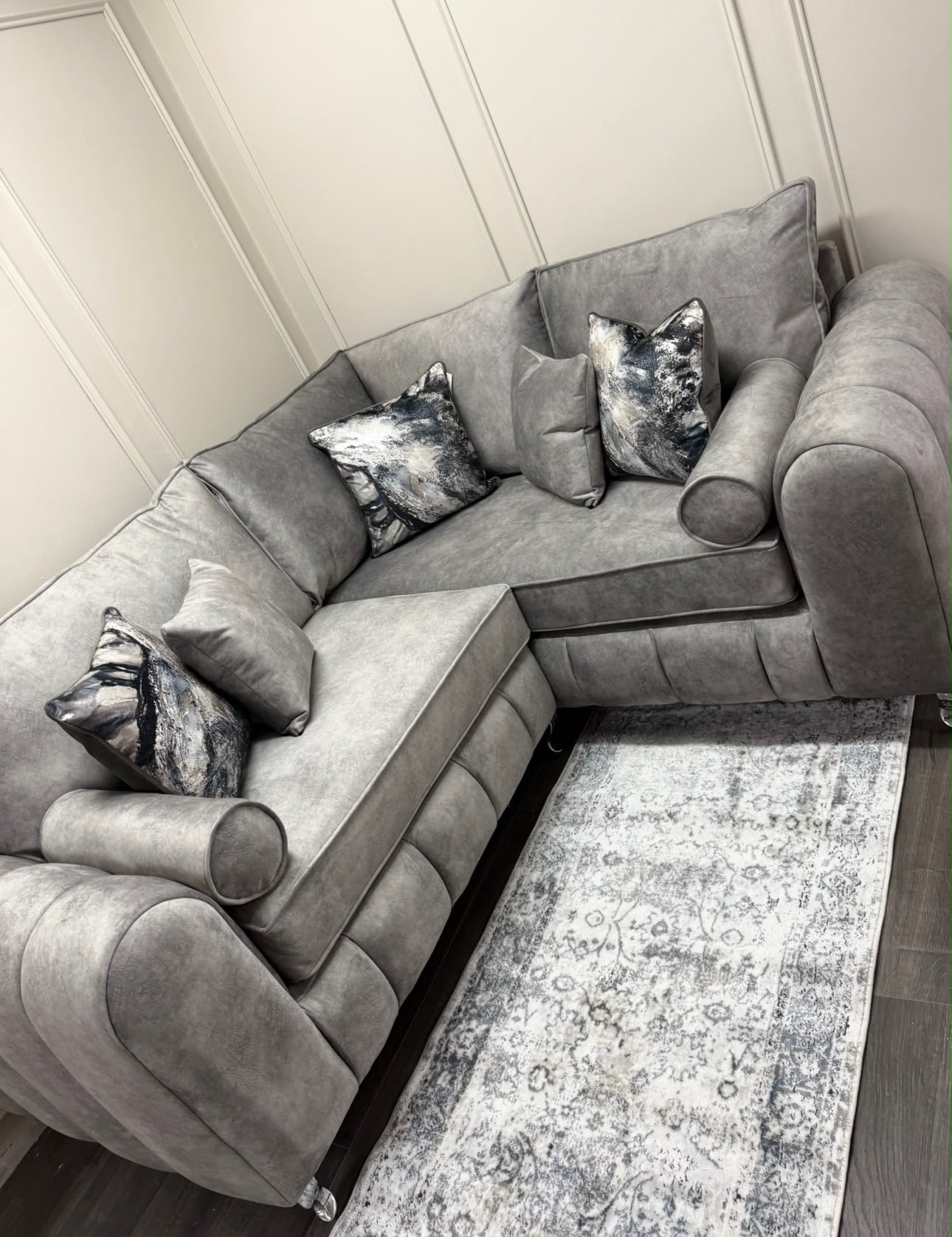 Grey corner sofa with rounded arms and patterned scatter cushions.