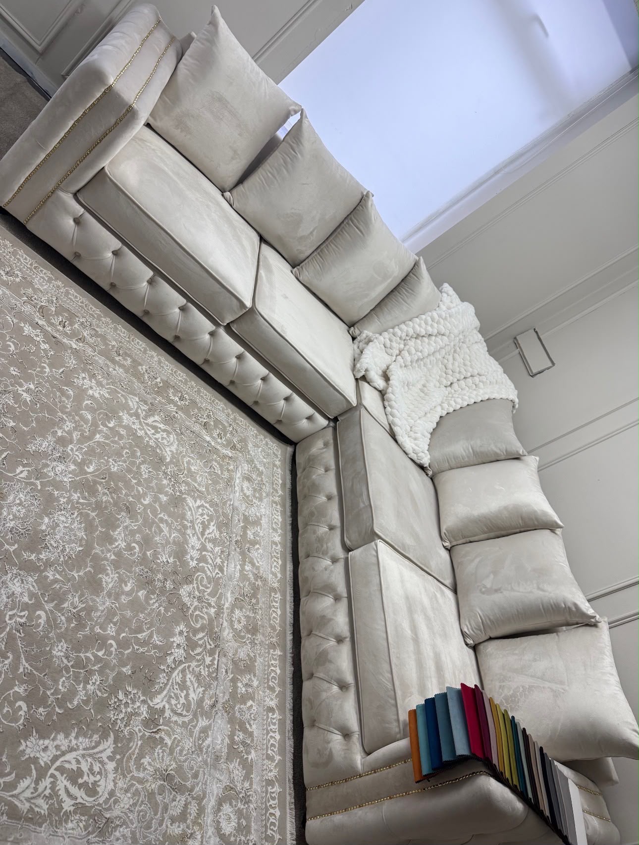 Large light upholstered U-shaped sofa with loose back cushions.