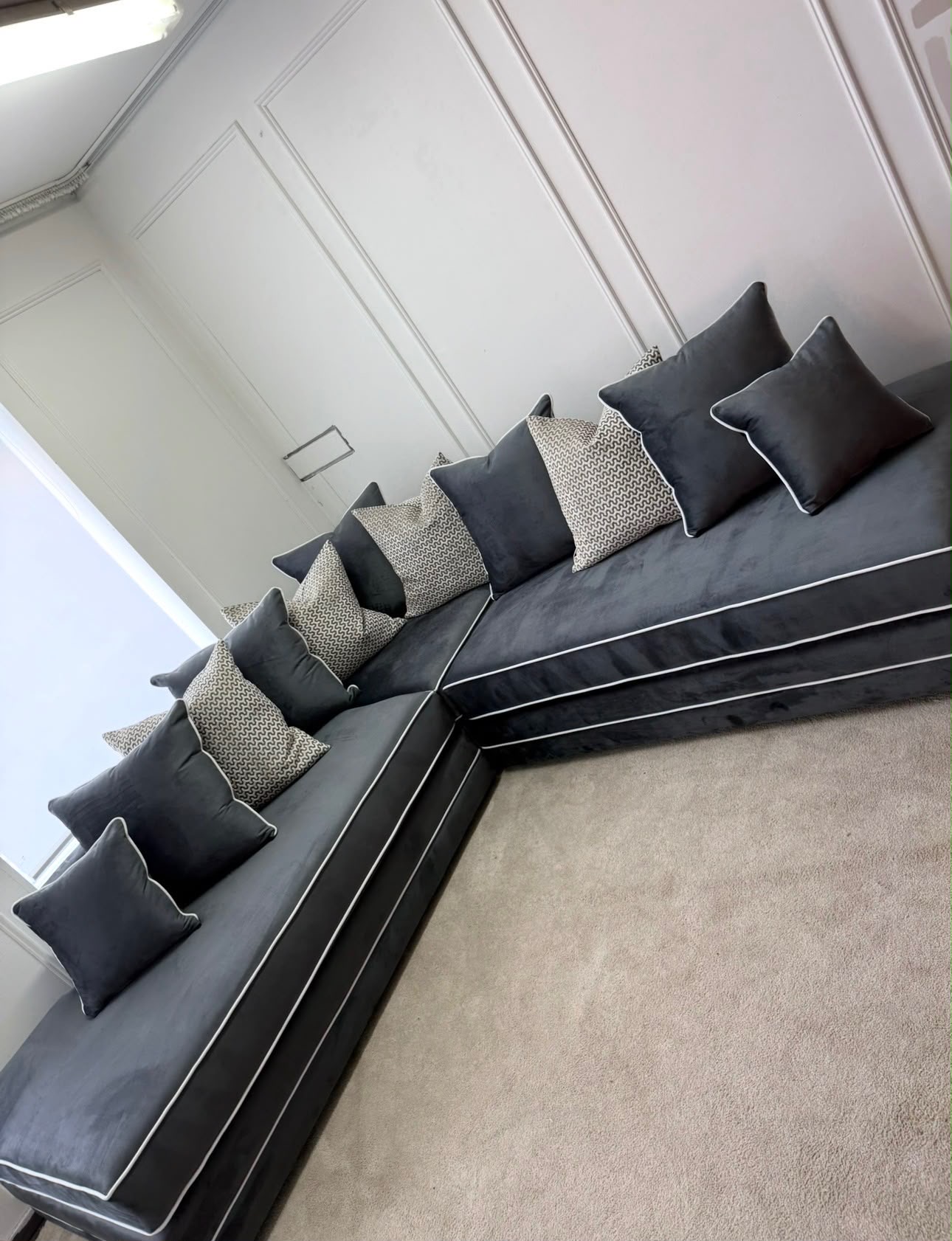 Dark corner sofa with low arms and loose back cushions.