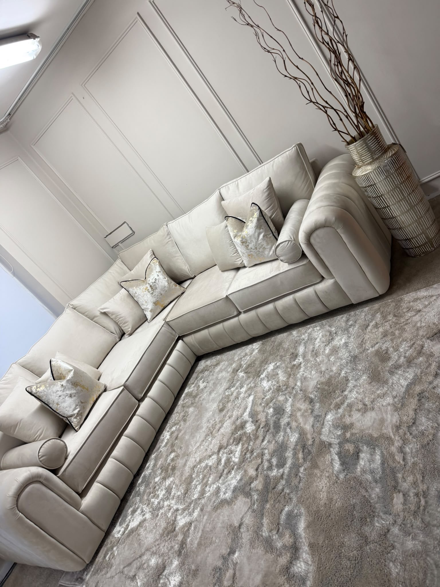 Light corner sofa with rolled arms and a vertically padded front.