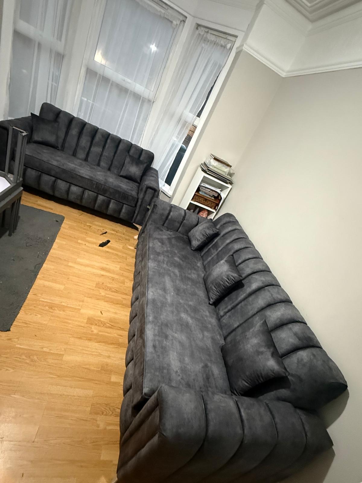 Dark sofa set with vertical padded detailing in a living room.
