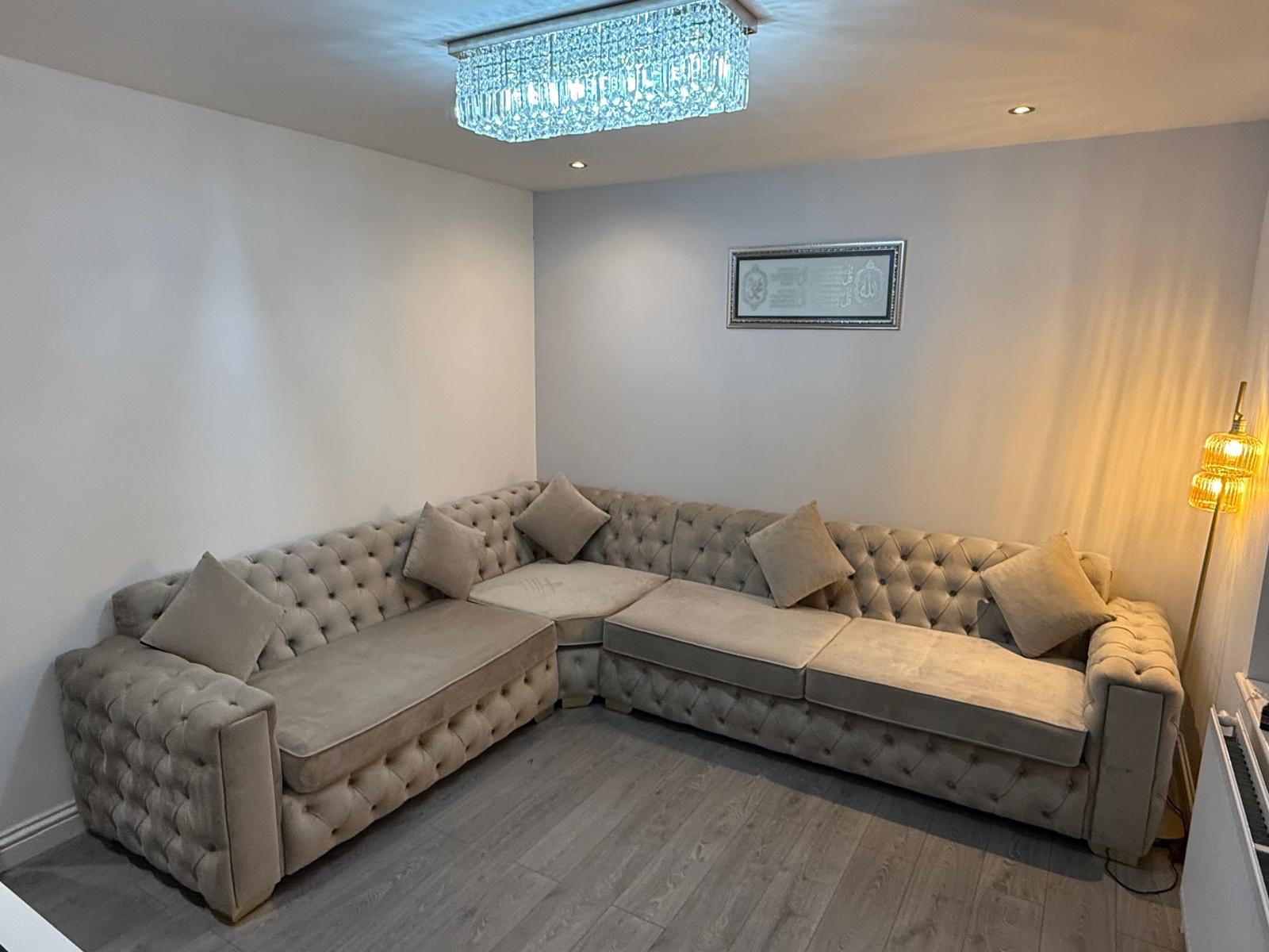 Light button-tufted corner sofa in a living room.