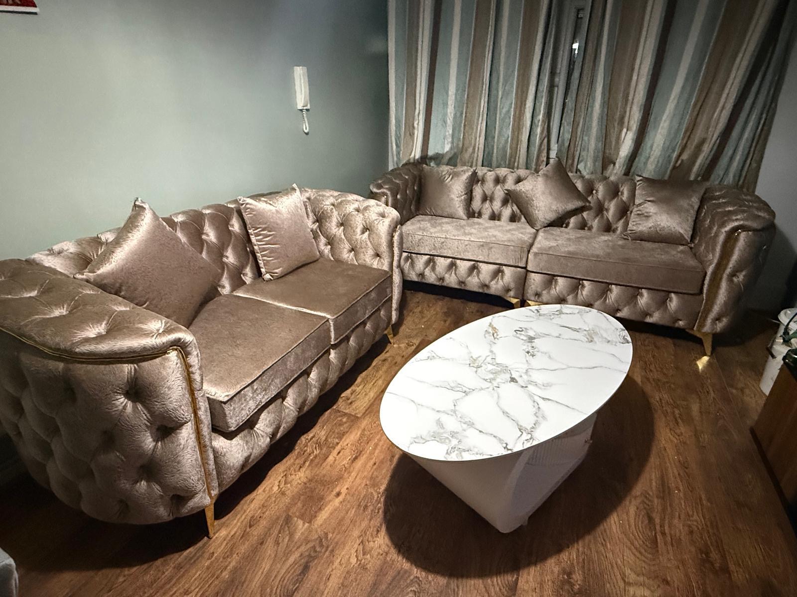 Neutral button-tufted sofa set with rounded arms.