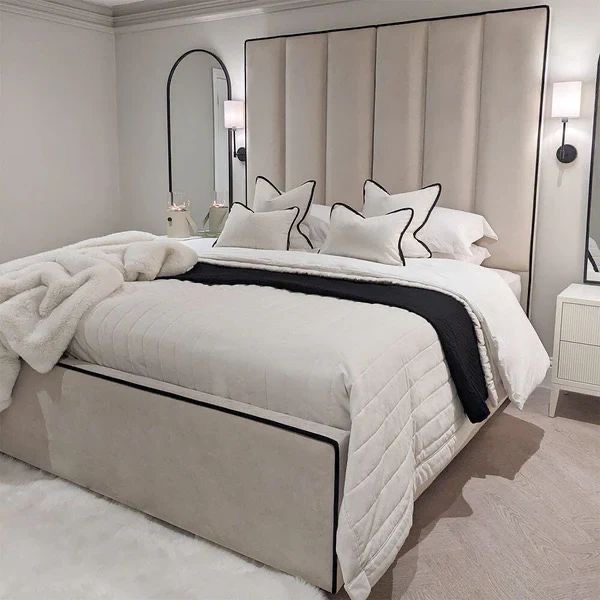 Light upholstered bed outlined with dark piping.