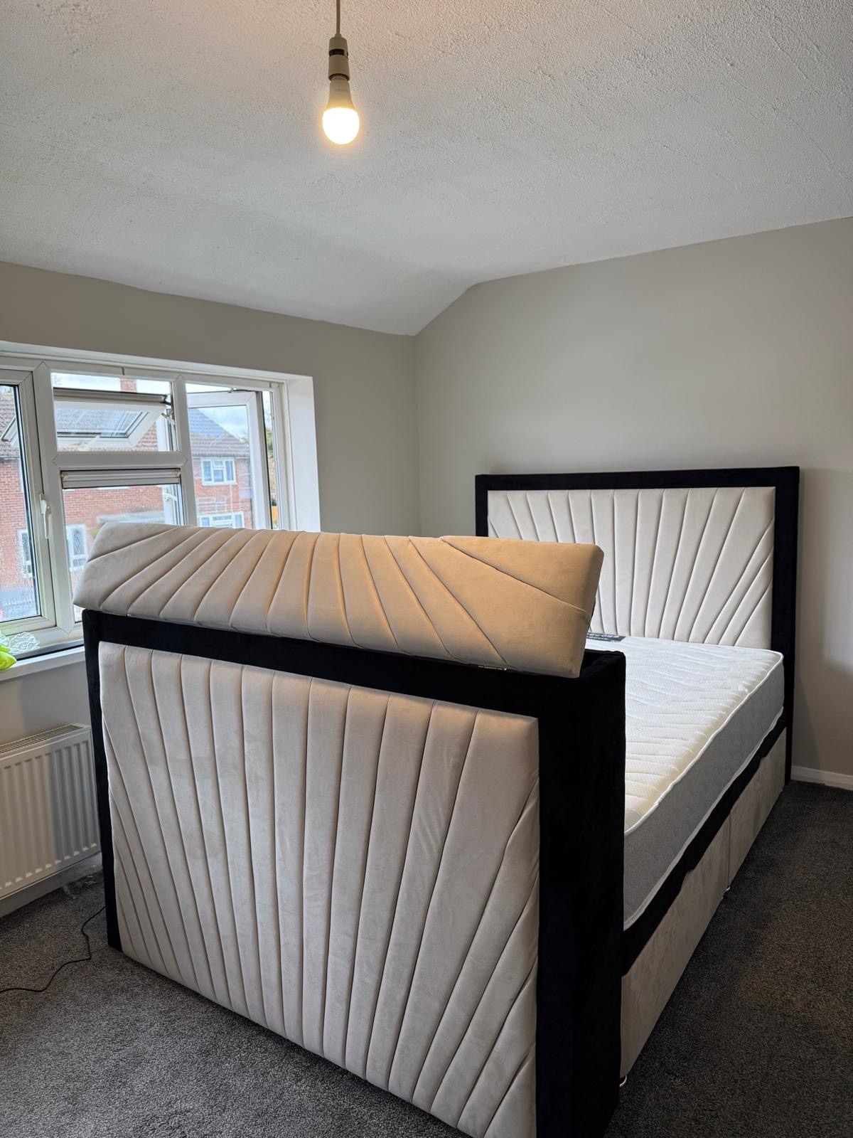 Light upholstered bed with a contrasting dark border and fan-shaped stitched panels.
