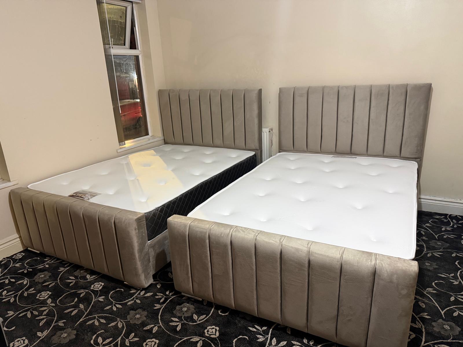 Two matching grey upholstered bed designs with vertically padded headboards and footboards.