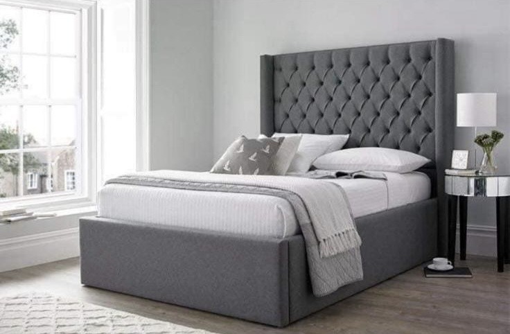 Grey upholstered bed with a button-tufted headboard and plain base.