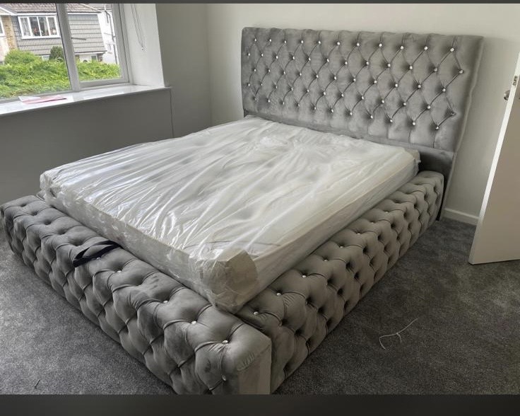 Silver button-tufted upholstered bed with a mattress.