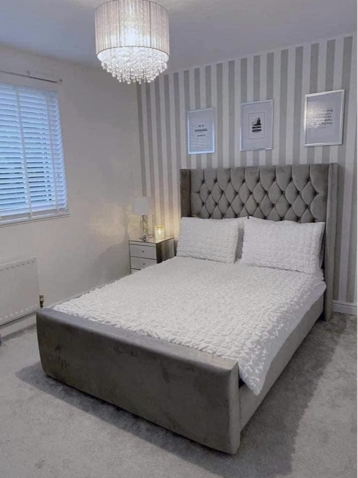 Grey upholstered bed with a tall button-tufted headboard and a plain footboard.