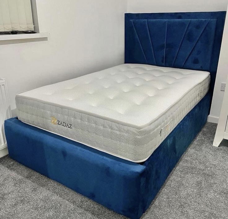 Blue upholstered storage bed with its mattress in place.